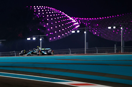 Fernando tackles a corner with the bright lights of the Yas Marina circuit in the background