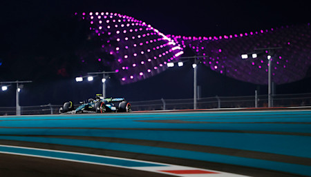 Fernando tackles a corner with the bright lights of the Yas Marina circuit in the background
